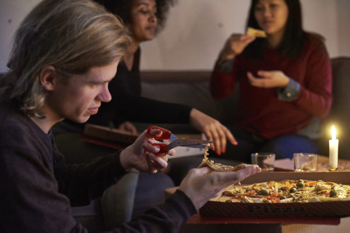 Människor hemma äter pizza vid tända ljus
