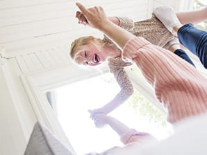 Glad flicka flyger på mammas fötter