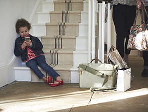 Barn sitter i trappen med mobil