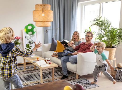 Familj sitter i vardagsrummet och tittar på barn som leker.