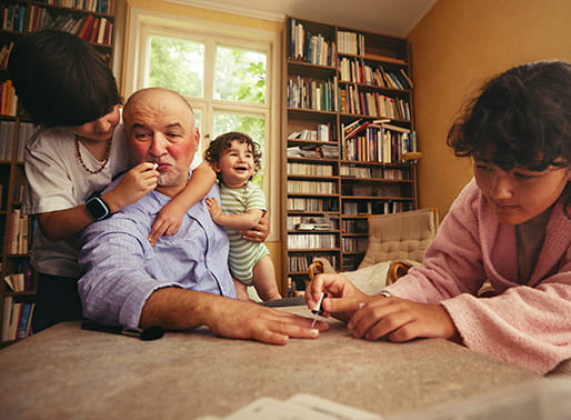 Familj i vardagsrum där barnen hjälper pappa med smink och nagellack