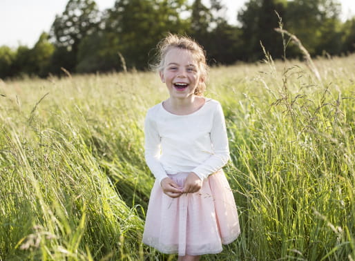 Flicka i ballerinakläder skrattar på en äng