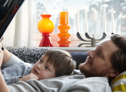 Pappa och son ligger i soffan och läser saga