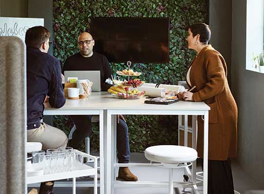 Tre personer pratar runt ett bord på ett kontor.