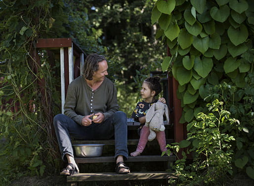 barn sitter med far och skalar potatis