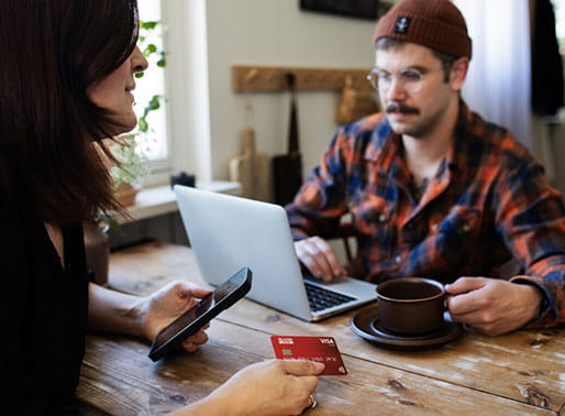 Par sitter vid köksbordet med datorn och ska använda Ikano Kort.