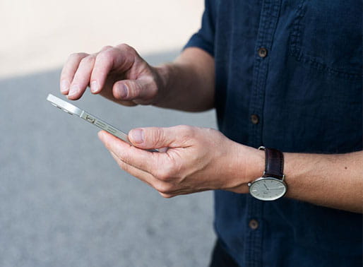 Närbild på händer som scrollar på telefon.