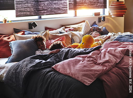 En familj som sover tillsammans i en stor säng.