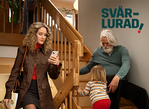 Kvinna går upp för trappa  läsandes ett sms medan morfar passar litet barn.