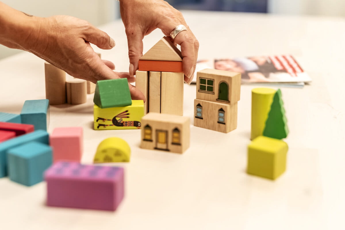 Person som bygger hus med byggklossar.